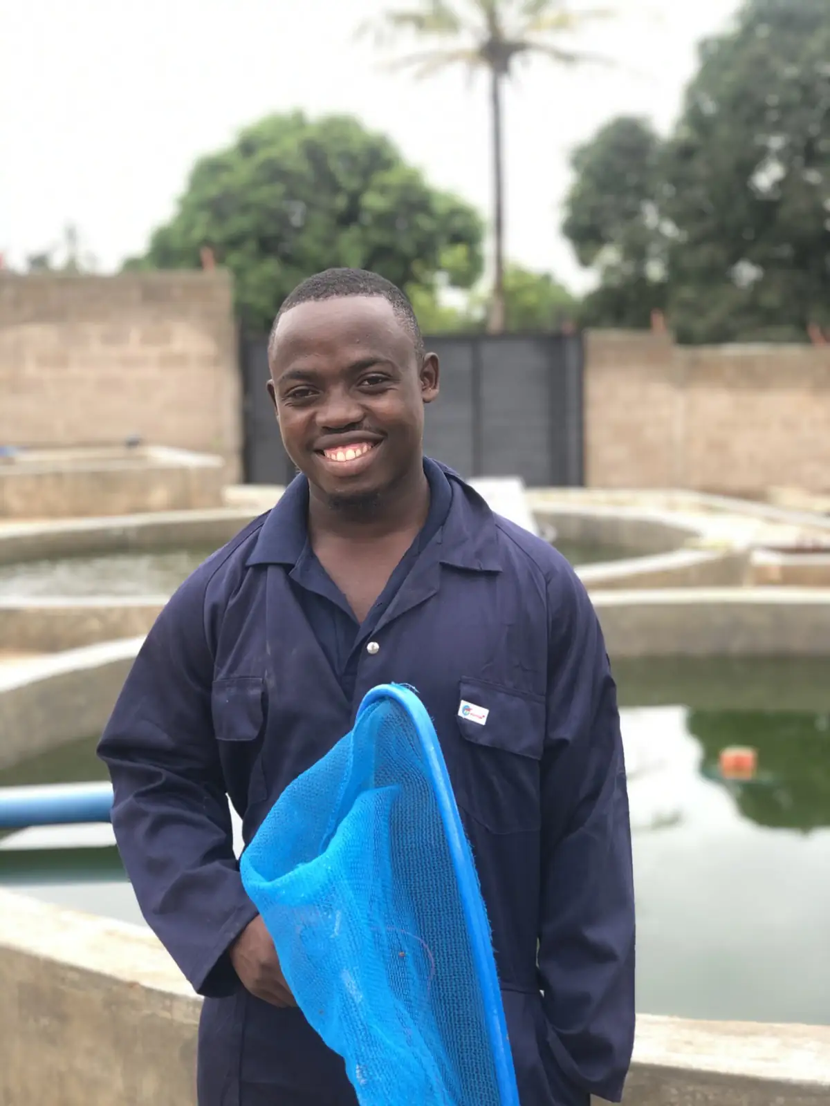 A hatchery worker holding a hand net beside the tanks